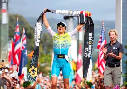 Anne Haug crossing the Ironman finish line with the finish tape